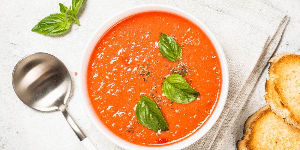 Creamy vegan tomato soup with fresh basil and black pepper