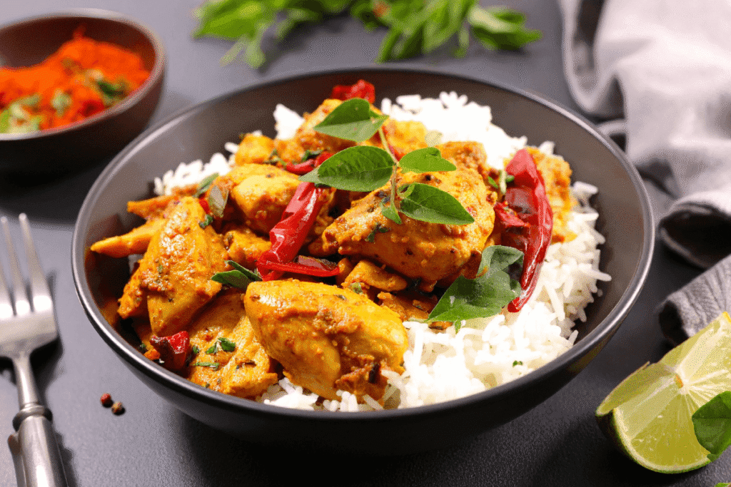 Healthy chicken and veggie meal prep bowl with rice, peppers, and fresh herbs served in a black dish