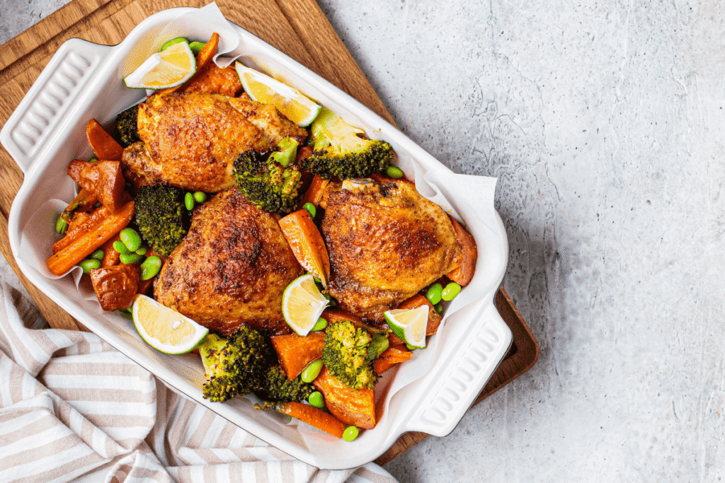Oven-roasted chicken with mixed vegetables on parchment paper, healthy meal prep style