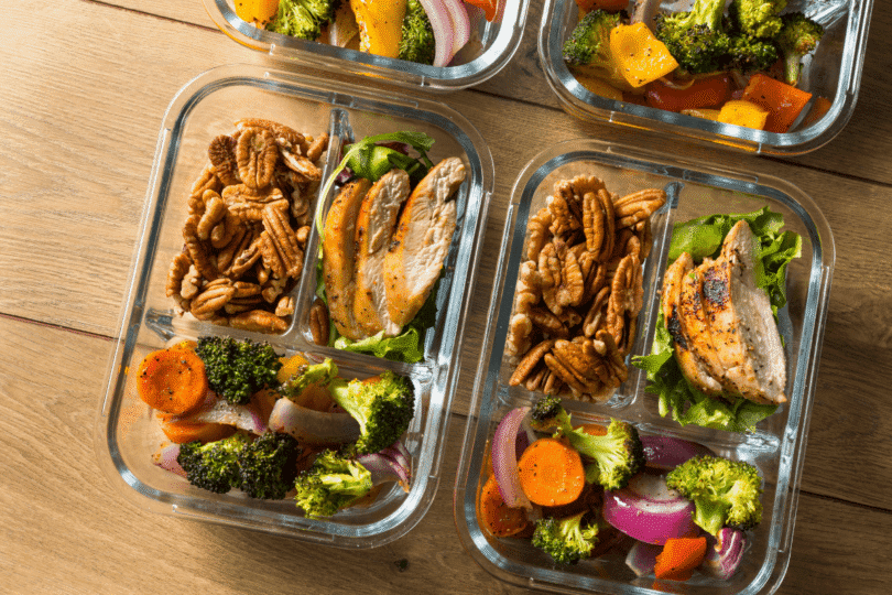 6 (6) Healthy chicken meal prep container with rice, vegetables, and fresh greens on a dark wooden background