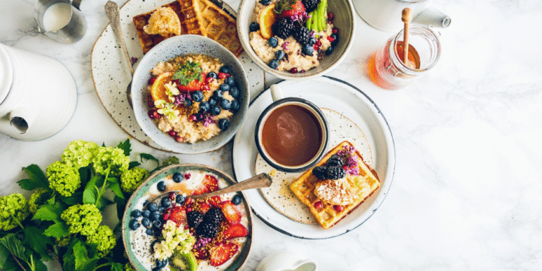 A variety of healthy, gluten-free breakfast dishes including bowls of oats, fruits, and nuts, arranged on a wooden table.