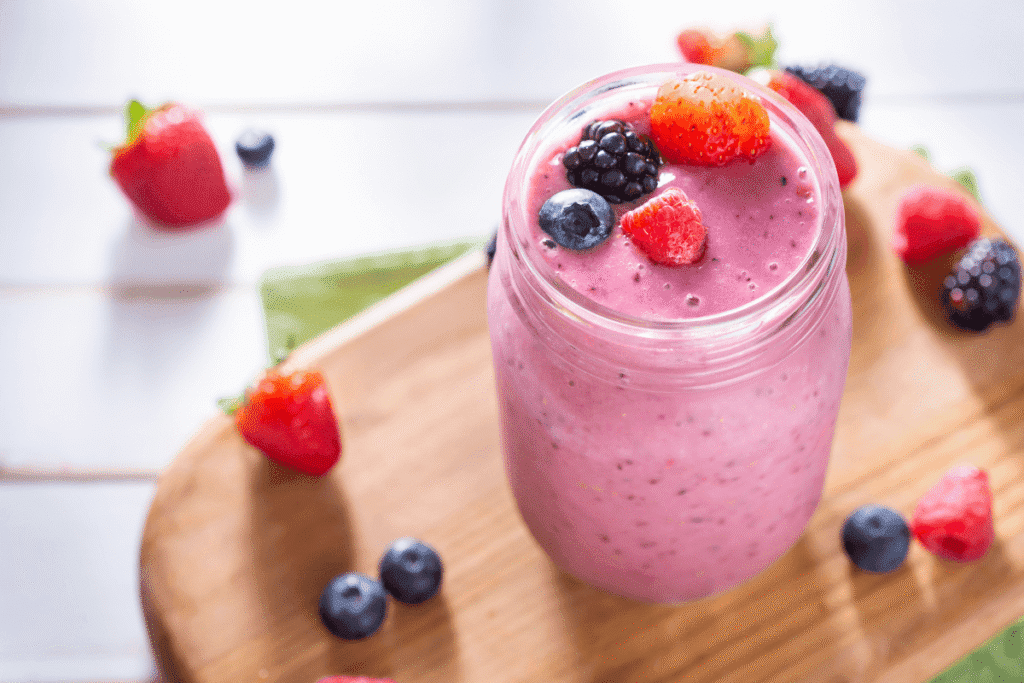 Berry protein smoothie in a glass topped with fresh blueberries and raspberries – a refreshing and healthy breakfast option