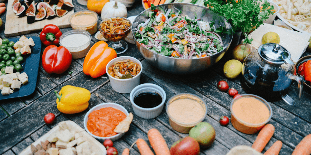 A variety of colorful plant-based ingredients including legumes, grains, and fresh vegetables arranged beautifully on a textured surface, showcasing the richness of plant-based meals.