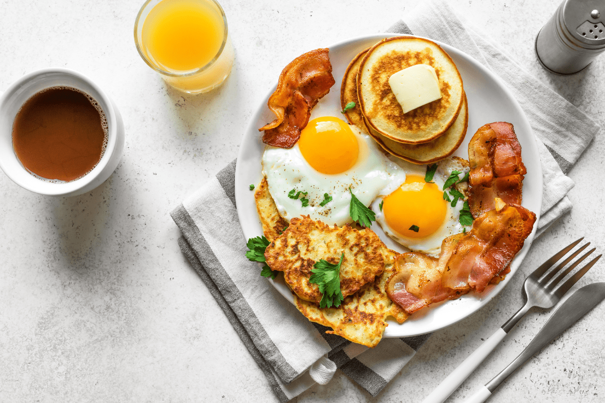 2 High-protein breakfast with eggs, avocado, pancakes, and fresh orange juice on a plate