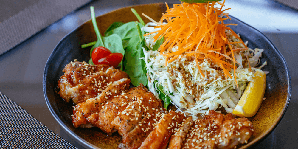 A delicious plant-based vegan protein meal with sesame-coated tofu, fresh vegetables, and a vibrant salad.