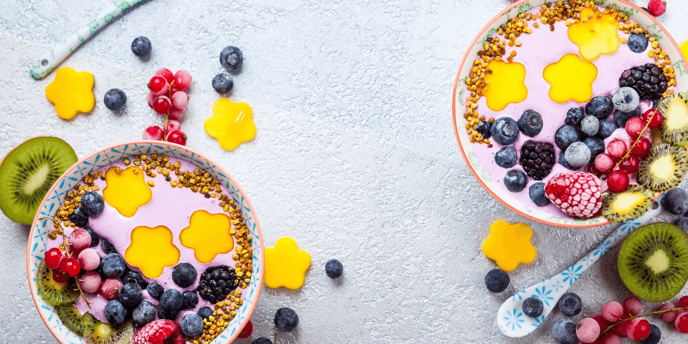 Two bowls filled with mixed fruits including berries and tropical fruits, arranged on a light background, perfect for a healthy breakfast or snack.