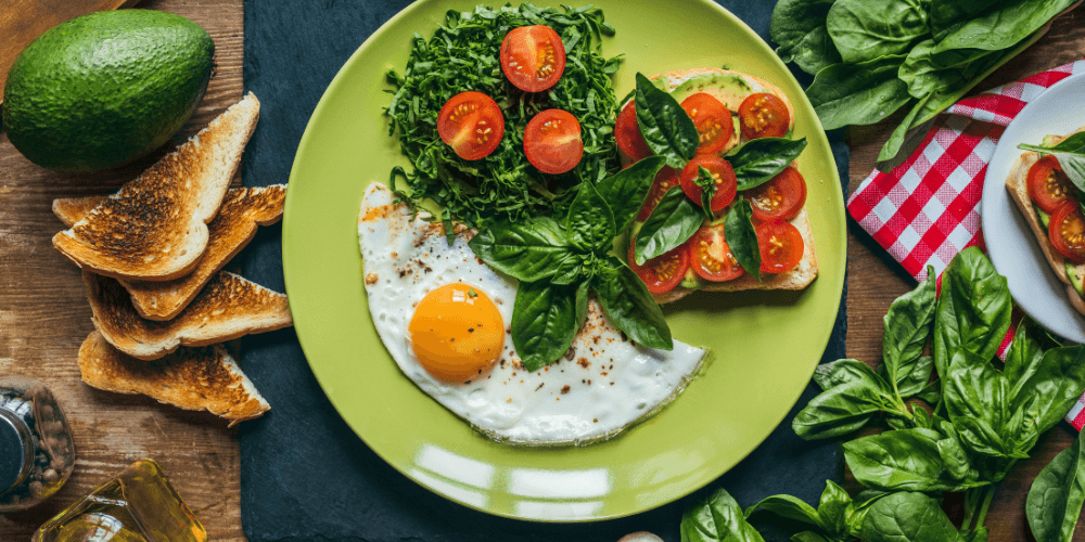 5 (10) A colorful plate with a healthy breakfast including fresh greens, tomatoes, an egg, and toasted bread slices, perfect for a nutritious meal.