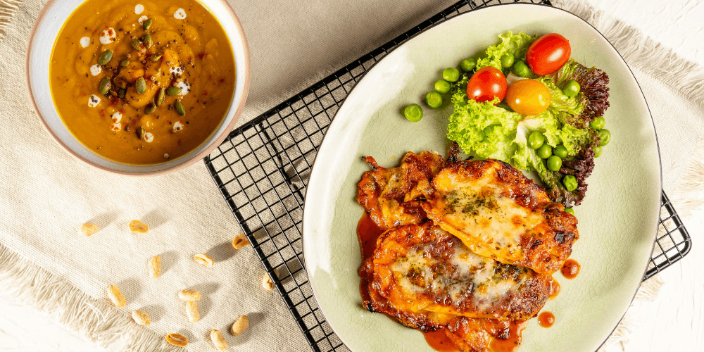 A healthy plant-based dish served with fresh vegetables and a flavorful sauce, presented on a white plate.
