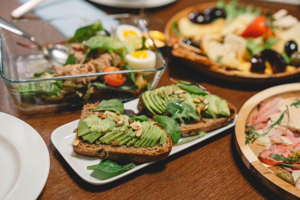 A variety of delicious, healthy dishes including pizza, salads, and other plant-based foods, arranged beautifully on a wooden table.