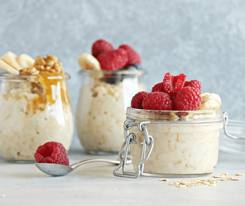 Glass jar filled with creamy overnight oats topped with fresh raspberries, almonds, and peanut butter – healthy breakfast idea