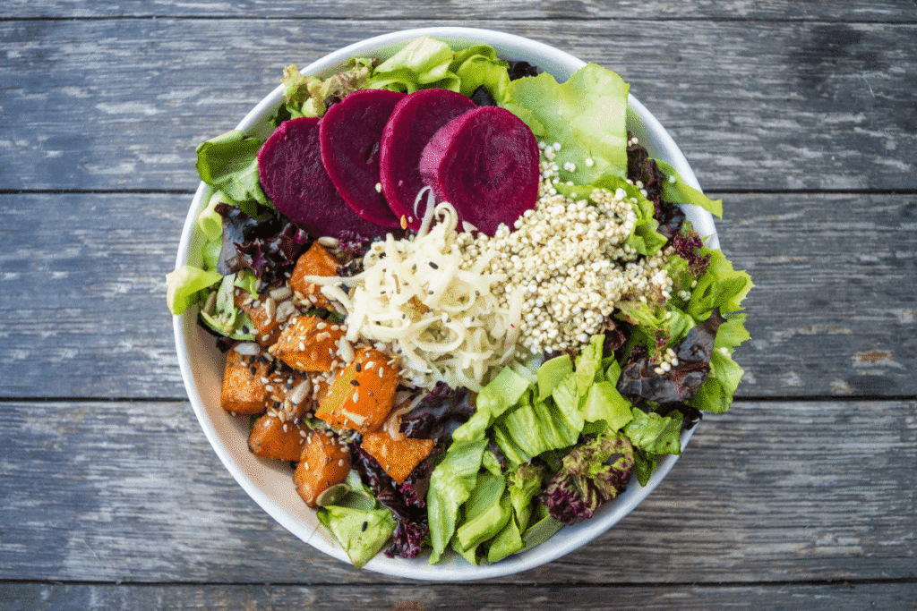 Fresh vegan buddha bowl with quinoa, spinach, beetroot, carrots, and avocado – healthy plant-based meal