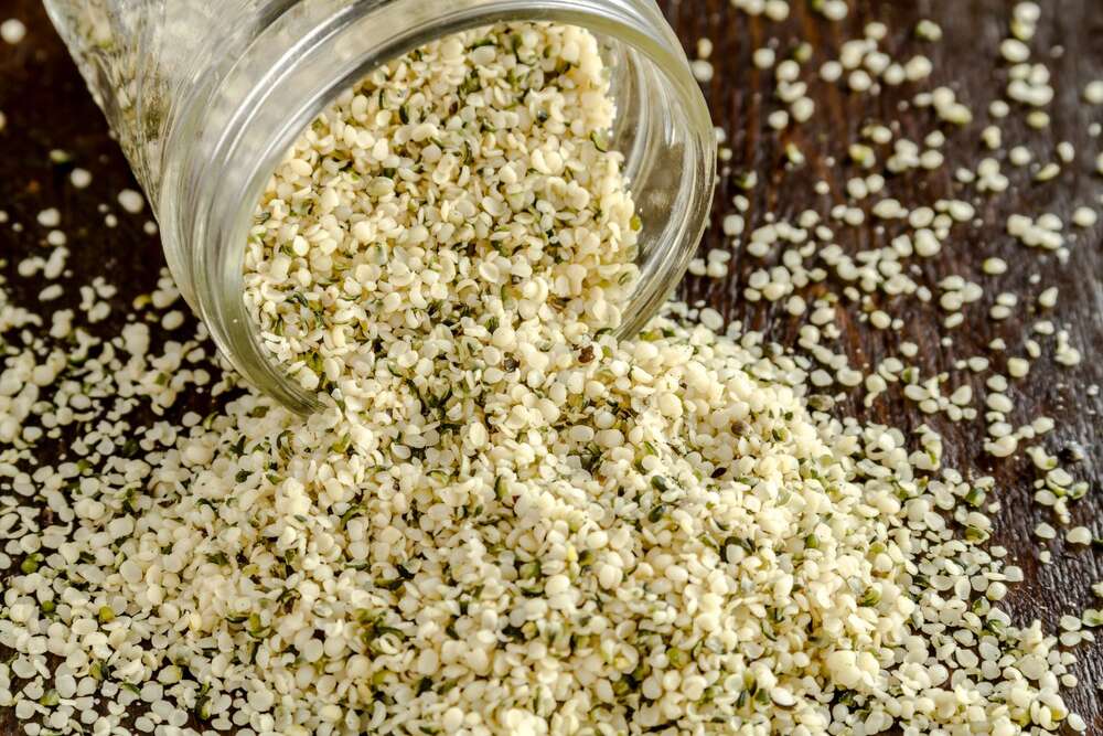 Hemp seeds spilling from a glass jar, high protein plant based superfood