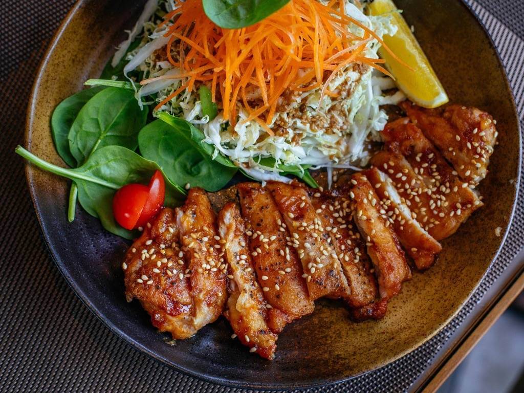 Grilled sesame chicken served with shredded cabbage, fresh spinach, and carrots – a colorful high-protein healthy dinner.