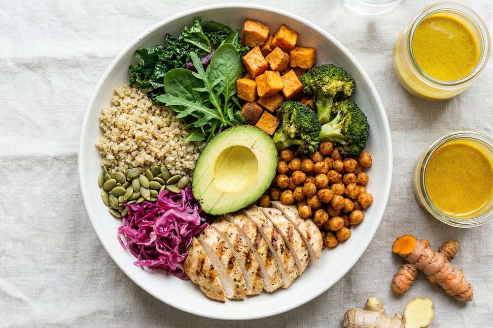 Anti-inflammatory Buddha bowl with quinoa roasted vegetables grilled chicken avocado and turmeric dressing