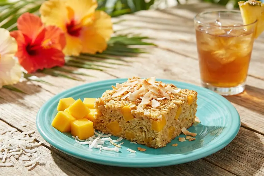 Tropical mango coconut baked oatmeal with toasted coconut topping and fresh mango on blue plate