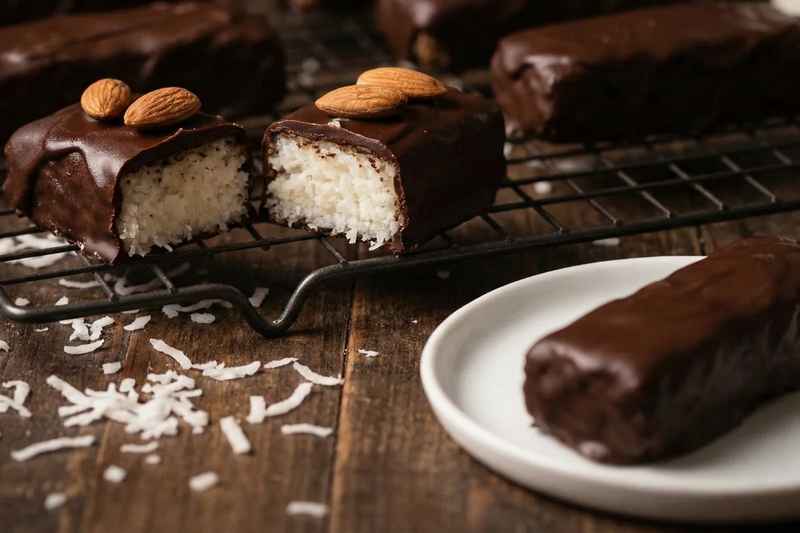 Chocolate covered almond joy bars showing coconut filling with whole almonds on top