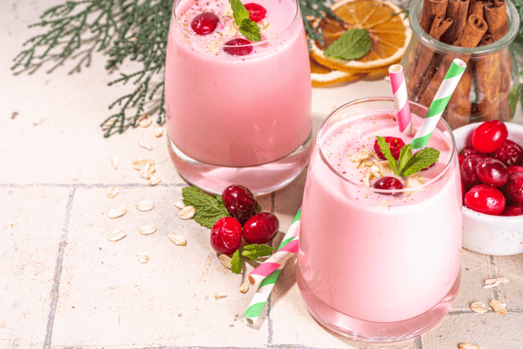 Strawberry banana high protein smoothie for weight loss in glass jars with fresh mint and cranberries on a light wooden surface