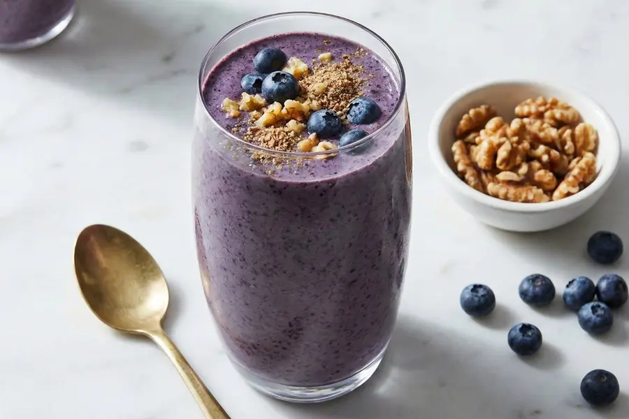 Blueberry walnut brain booster smoothie in elegant glass with fresh berries and walnuts on marble