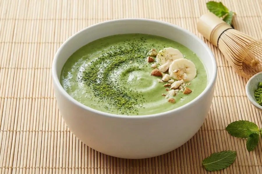 Matcha mind clarity smoothie in white ceramic bowl with matcha powder and banana