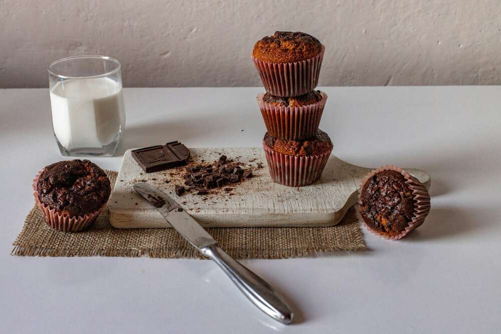 Chocolate chip protein muffins meal prep stacked with milk glass and chocolate
